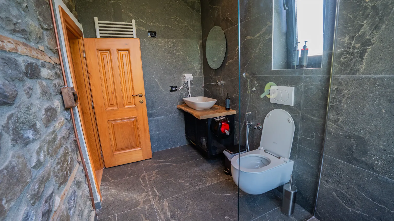 En-suite bathroom with a wooden door and stone wall