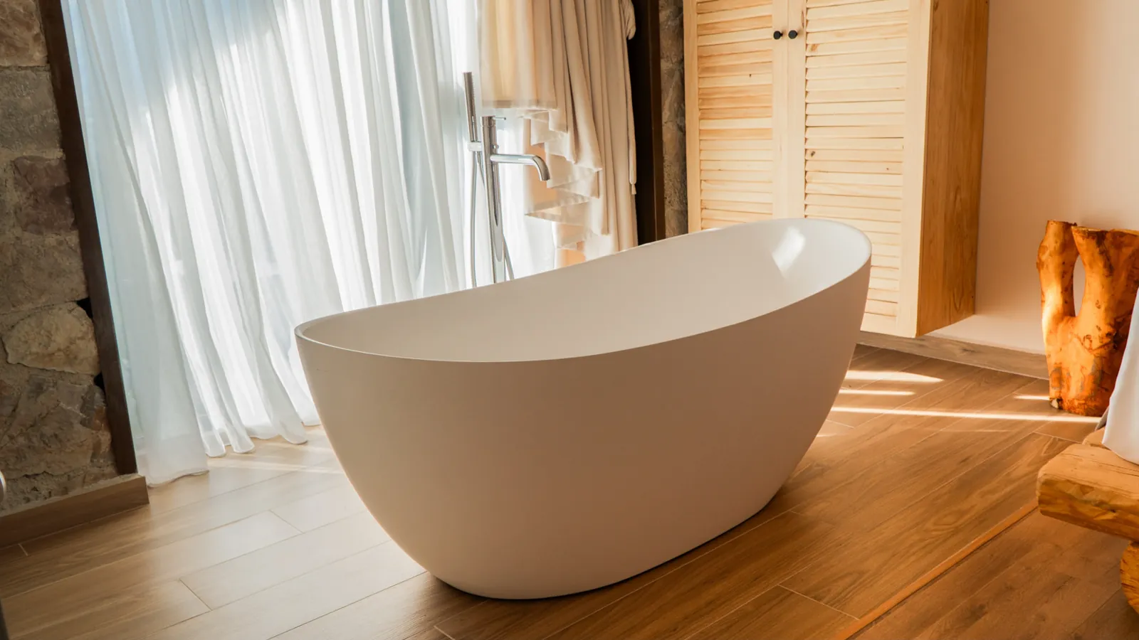Freestanding bathtub beside a bright window